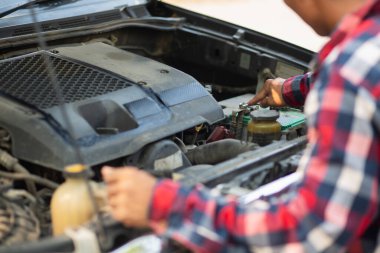 Adam uzun mesafeler kat etmeden önce düzgün ve güvenli bir şekilde tamir etmek için aracın motorunu ve durumunu kontrol ediyor. Adam güvenli bir yere gitmeden önce arabanın ve motorun durumunu kontrol ediyor..