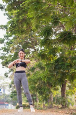 Güzel bir Asyalı kadının spor bardaki portresi akıllı saatine bakıyor kalp atışlarını ve adımlarını kontrol ediyor koşudan sonra akıllı saat teknolojisi kullanıyor sağlık ve kalp atışlarını kontrol ediyor.