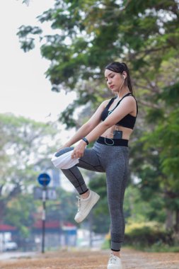 Güzel Asyalı kadın koşu sırasında kas hasarlarını azaltmak için kaslarını çalıştırmak için vücudunu ısıtıyor. Güzel Asyalı kadın koşuya hazırlanmak için kaslarını esnetiyor. .