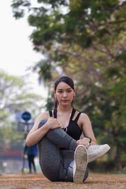 Güzel Asyalı kadın koşu sırasında kas hasarlarını azaltmak için kaslarını çalıştırmak için vücudunu ısıtıyor. Güzel Asyalı kadın koşuya hazırlanmak için kaslarını esnetiyor. .