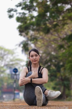 Güzel Asyalı kadın koşu sırasında kas hasarlarını azaltmak için kaslarını çalıştırmak için vücudunu ısıtıyor. Güzel Asyalı kadın koşuya hazırlanmak için kaslarını esnetiyor. .