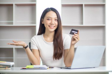 Asyalı iş kadınının portresi ofis malzemelerini sipariş etmek için kredi kartı kullanıyor İçişleri Bakanlığını KOBİ işine hazırlamak için ve kredi kartıyla ürünleri satışa çıkarmak için kullanıyor. Boşluğu kopyala