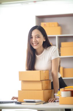 KOBİ işini İçişleri Bakanlığı 'nı kullanarak başlatan ve paketleri tek başına hazırlayan güzel Asyalı iş kadını, müşterilere nakliye yoluyla teslimat için hazırlanmak üzere birçok paket taşıyor.