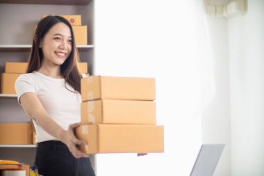 KOBİ işini İçişleri Bakanlığı 'nı kullanarak başlatan ve paketleri tek başına hazırlayan güzel Asyalı iş kadını, müşterilere nakliye yoluyla teslimat için hazırlanmak üzere birçok paket taşıyor.