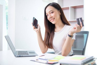 Asyalı iş kadınının portresi ofis malzemelerini sipariş etmek için kredi kartı kullanıyor İçişleri Bakanlığını KOBİ işine hazırlamak için ve kredi kartıyla ürünleri satışa çıkarmak için kullanıyor. Boşluğu kopyala