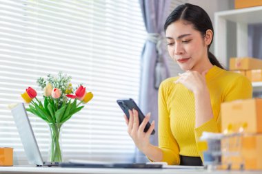 İş kadını, müşterilerden sipariş almak için cep telefonu uygulaması üzerinden ev ofisi kurar ve müşterilerle iletişime geçmek ve siparişleri göndermeden önce onaylamak için cep telefonunu kullanır. Boşluğu kopyala