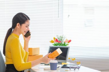 İş kadını, müşterilerden sipariş almak için cep telefonu uygulaması üzerinden ev ofisi kurar ve müşterilerle iletişime geçmek ve siparişleri göndermeden önce onaylamak için cep telefonunu kullanır. Boşluğu kopyala