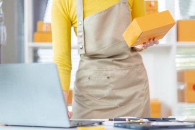 Asyalı işkadını siparişleri ve müşterilerin siparişlerini kontrol ediyor ve siparişleri online alışveriş uygulaması yoluyla teslim ediyor. Uygulama yoluyla çevrimiçi iş fikri