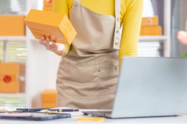 Asyalı işkadını siparişleri ve müşterilerin siparişlerini kontrol ediyor ve siparişleri online alışveriş uygulaması yoluyla teslim ediyor. Uygulama yoluyla çevrimiçi iş fikri