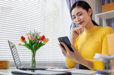 İş kadını, müşterilerden sipariş almak için cep telefonu uygulaması üzerinden ev ofisi kurar ve müşterilerle iletişime geçmek ve siparişleri göndermeden önce onaylamak için cep telefonunu kullanır. Boşluğu kopyala