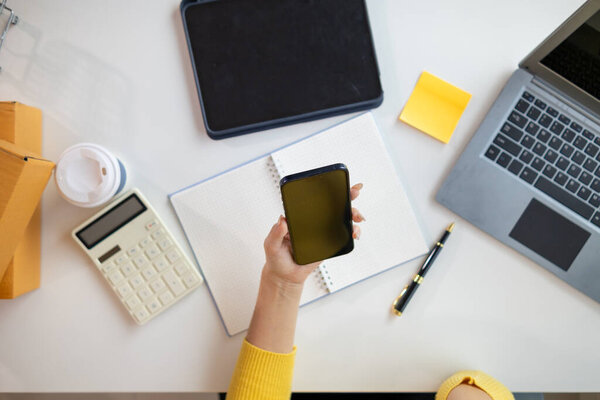 Деловая женщина создает домашний офис для получения заказов от клиентов через приложение мобильного телефона и использует свой мобильный телефон, чтобы связаться с клиентами и подтвердить заказы, прежде чем отправить их. копировальное пространство