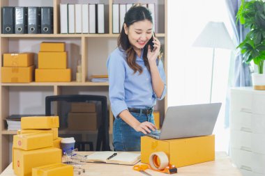 Asyalı kadın evini ofis olarak kullanarak küçük bir KOBİ işine başladı. Paketlemeden ve müşterilere göndermeden önce ürünleri Düzen 'e göre onaylamak için müşterileri arıyor. Boşluğu Kopyala