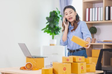 Asyalı kadın evini ofis olarak kullanarak küçük bir KOBİ işine başladı. Paketlemeden ve müşterilere göndermeden önce ürünleri Düzen 'e göre onaylamak için müşterileri arıyor. Boşluğu Kopyala