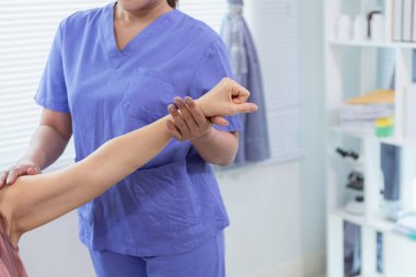 Kadın bir doktor, yaşlı bir insanın vücuduna kas gücünü geri getirmek için masaj yapıyor ya da hastanın kaslarının daha verimli çalışması için fizik tedavi uyguluyor. Boşluğu kopyala