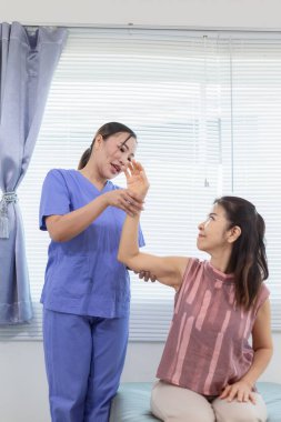 Kadın doktor yaşlı bir insana bakıyor ve yaşlı bir insanın fiziksel terapi görmesine, kasların çalışmasına ve kas sisteminin işlevlerini kontrol etmesine yardım ediyor..