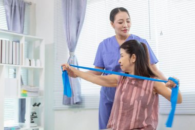 Kadın doktor yaşlı bir insana bakıyor ve yaşlı bir insanın fiziksel terapi görmesine, kasların çalışmasına ve kas sisteminin işlevlerini kontrol etmesine yardım ediyor..