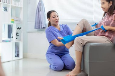 Kadın doktor yaşlı bir insana bakıyor ve yaşlı bir insanın fiziksel terapi görmesine, kasların çalışmasına ve kas sisteminin işlevlerini kontrol etmesine yardım ediyor..