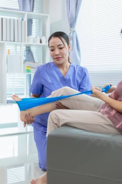 Kadın doktor yaşlı bir insana bakıyor ve yaşlı bir insanın fiziksel terapi görmesine, kasların çalışmasına ve kas sisteminin işlevlerini kontrol etmesine yardım ediyor..