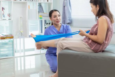 Kadın doktor yaşlı bir insana bakıyor ve yaşlı bir insanın fiziksel terapi görmesine, kasların çalışmasına ve kas sisteminin işlevlerini kontrol etmesine yardım ediyor..