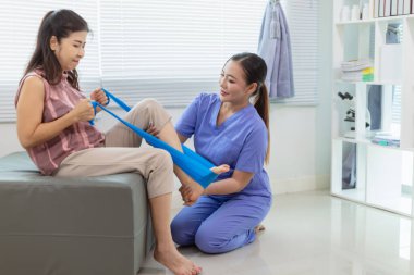 Kadın doktor yaşlı bir insana bakıyor ve yaşlı bir insanın fiziksel terapi görmesine, kasların çalışmasına ve kas sisteminin işlevlerini kontrol etmesine yardım ediyor..