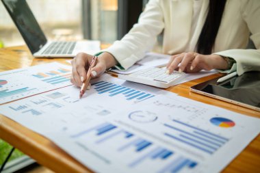 İş kadını, pazarlamayı geliştirmek için masadaki birçok belgenin yıllık performansını analiz ediyor. İş kadını bir çok belgedeki iş bilgilerini kontrol ediyor