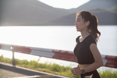 Sokakta koşan Asyalı kadın koşucunun portresi çünkü koşmak sağlık için iyi bir egzersizdir. Güzel Asyalı bayan koşucu, iyi bir sağlık egzersizi için sabah sokakta tek başına koşuyor..