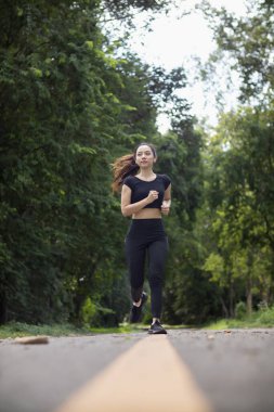 Sokakta koşan Asyalı kadın koşucunun portresi çünkü koşmak sağlık için iyi bir egzersizdir. Güzel Asyalı bayan koşucu, iyi bir sağlık egzersizi için sabah sokakta tek başına koşuyor..