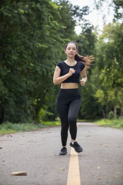 Sokakta koşan Asyalı kadın koşucunun portresi çünkü koşmak sağlık için iyi bir egzersizdir. Güzel Asyalı bayan koşucu, iyi bir sağlık egzersizi için sabah sokakta tek başına koşuyor..