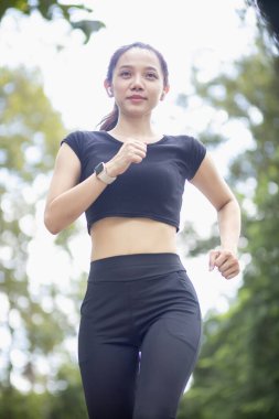 Sokakta koşan Asyalı kadın koşucunun portresi çünkü koşmak sağlık için iyi bir egzersizdir. Güzel Asyalı bayan koşucu, iyi bir sağlık egzersizi için sabah sokakta tek başına koşuyor..