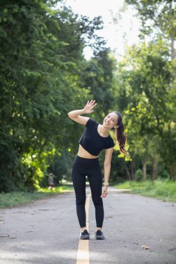 Spor kıyafetleri giyen ve vücudunu ısıtan güzel bayan koşucunun portresi. Sabah koşuya hazır ol. Sağlığına dikkat et. Kadın koşucu tek başına vücudunu ısıtır parkta koşuya hazırlanır..