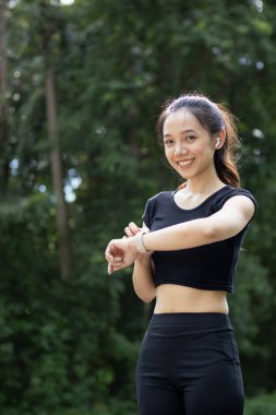 Bileğindeki akıllı saate bakan bir koşucunun portresi kalp atışlarını ve koşu mesafesini kontrol ediyor. Koşucu dikkat ediyor. Akıllı saati bileğinde. Nabzını ve koşu mesafesini kontrol ediyor..