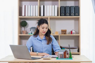 Emlakçılar müşteri bilgilerini kontrol ediyor ve emlak satışı için kontrat hazırlıyorlar. Gayrimenkul işlemlerinin yasal olarak tamamlanması için emlak sözleşmesi imzalanmaya hazır..