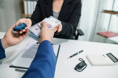 Alıcı, satış sözleşmesini tamamladıktan ve satıcıya ödeme yaptıktan sonra araba satıcısından araba anahtarlarını alıyor. Satıcı, satış sözleşmesini tamamladıktan sonra arabanın anahtarlarını ofisteki müşteriye verir..