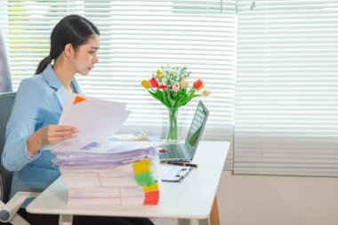 İş kadını, masasındaki çok sayıda belgenin hesaplarını kontrol etmek ve iş planını analiz etmek için belge arayışında olduğunu vurguladı. İş kadını çok sayıda belgenin altını çizdi