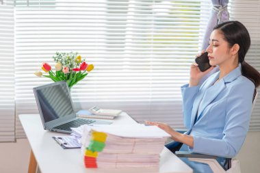 İş kadını, masasındaki çok sayıda belgenin hesaplarını kontrol etmek ve iş planını analiz etmek için belge arayışında olduğunu vurguladı. İş kadını çok sayıda belgenin altını çizdi