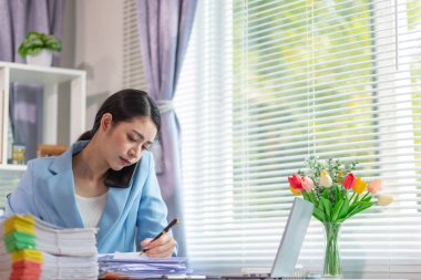 İş kadını, masasındaki çok sayıda belgenin hesaplarını kontrol etmek ve iş planını analiz etmek için belge arayışında olduğunu vurguladı. İş kadını çok sayıda belgenin altını çizdi