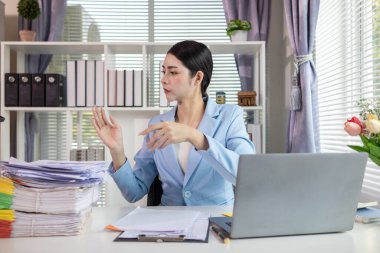 İş kadını masasında yığılmış çok sayıdaki yatırım belgelerini incelemek için belgeleri inceliyor. İş kadını masasında yığılmış çok sayıda belge bulmakta zorlanıyor..