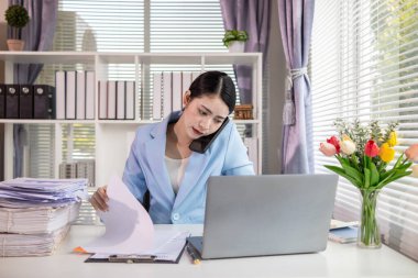 İş kadını, masasındaki çok sayıda belgenin hesaplarını kontrol etmek ve iş planını analiz etmek için belge arayışında olduğunu vurguladı. İş kadını çok sayıda belgenin altını çizdi