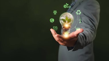 Ampul tutan adam, karbondioksit. İklim değişikliği için sera gazı emisyonunu azaltma, dünyayı kurtarma, küresel ısınmayı önleme, enerji tasarrufu, yenilenebilir enerji kullanımı, çevreyi koruma kavramı