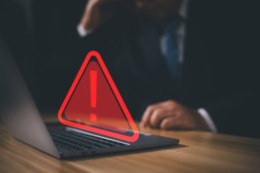Üçgen uyarı işareti, kodlama, şifreleme, hacker, suç, virüs içeren dizüstü bilgisayar kullanan bir bilgisayar korsanı veya programcı. Kırmızı uyarı işareti olan bilgisayar.