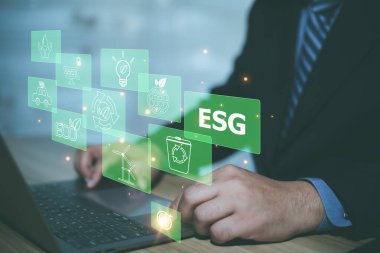 Adam ESG, ESG çevre sosyal yönetim yatırım konseptini analiz etmek için bilgisayar kullanıyor. İş yatırım stratejisi kavramında bilgisayar ekranında ESG simgeleri ortaya çıkıyor.