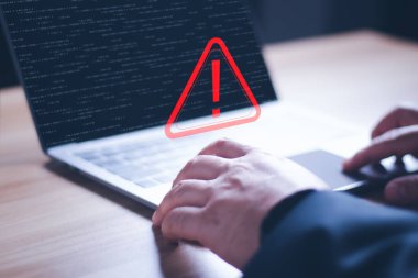 Üçgen uyarı işareti, kodlama, şifreleme, hacker, suç, virüs içeren dizüstü bilgisayar kullanan bir bilgisayar korsanı veya programcı. Kırmızı uyarı işareti olan bilgisayar.