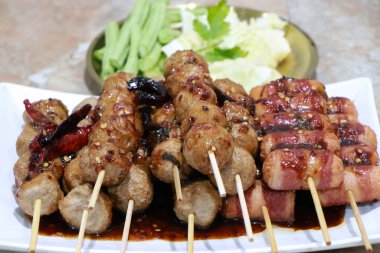 Izgara köfte. Balık köftesi ve sosisli sandviç tepside ızgara, kızarmış domuz köftesi beyaz tabakta bambu, masada baharatlı sos, Tayland sokak yemeği.. 