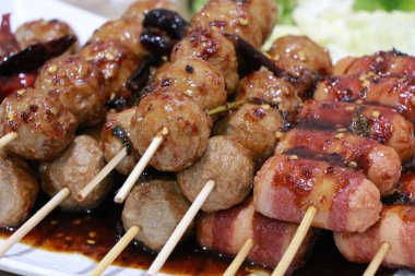 Izgara köfte. Balık köftesi ve sosisli sandviç tepside ızgara, kızarmış domuz köftesi beyaz tabakta bambu, masada baharatlı sos, Tayland sokak yemeği.. 