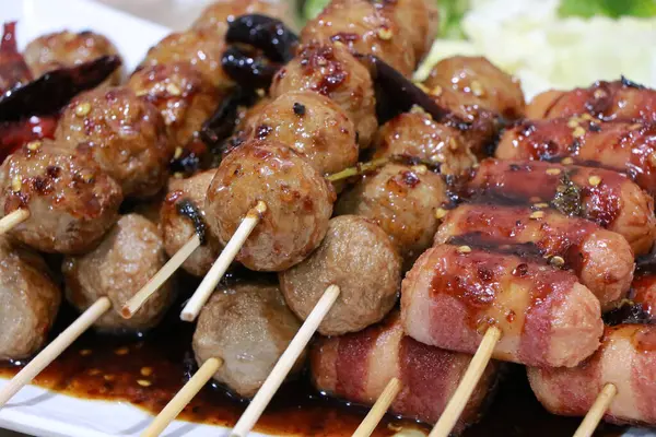 Izgara köfte. Balık köftesi ve sosisli sandviç tepside ızgara, kızarmış domuz köftesi beyaz tabakta bambu, masada baharatlı sos, Tayland sokak yemeği.. 