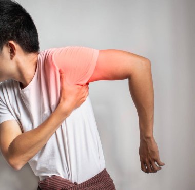 Pain in the shoulder joint and arm of Southeast Asian man. Concept of frozen shoulder.