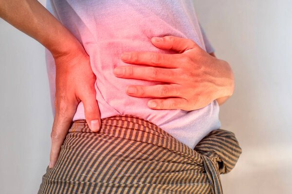 Азиатский молодой человек страдает от боли в спине и пояснице. Это может быть вызвано почечным камнем.