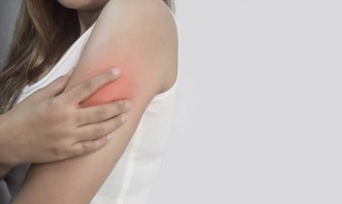 Genç bir kadın kolunu tutuyor, kırmızı bir bölge ağrıyı işaret ediyor..