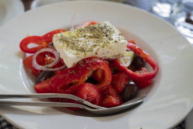 Kırmızı biber salatası, Feta peyniri, kırmızı soğan ve zeytin, derin bir tabakta servis edilir.