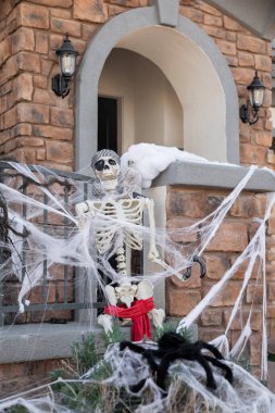Korkunç Cadılar Bayramı iskeleti ve evin ön bahçesinde siyah örümcek sonbahar titreşimleri ve sonbahar tatili konsepti.